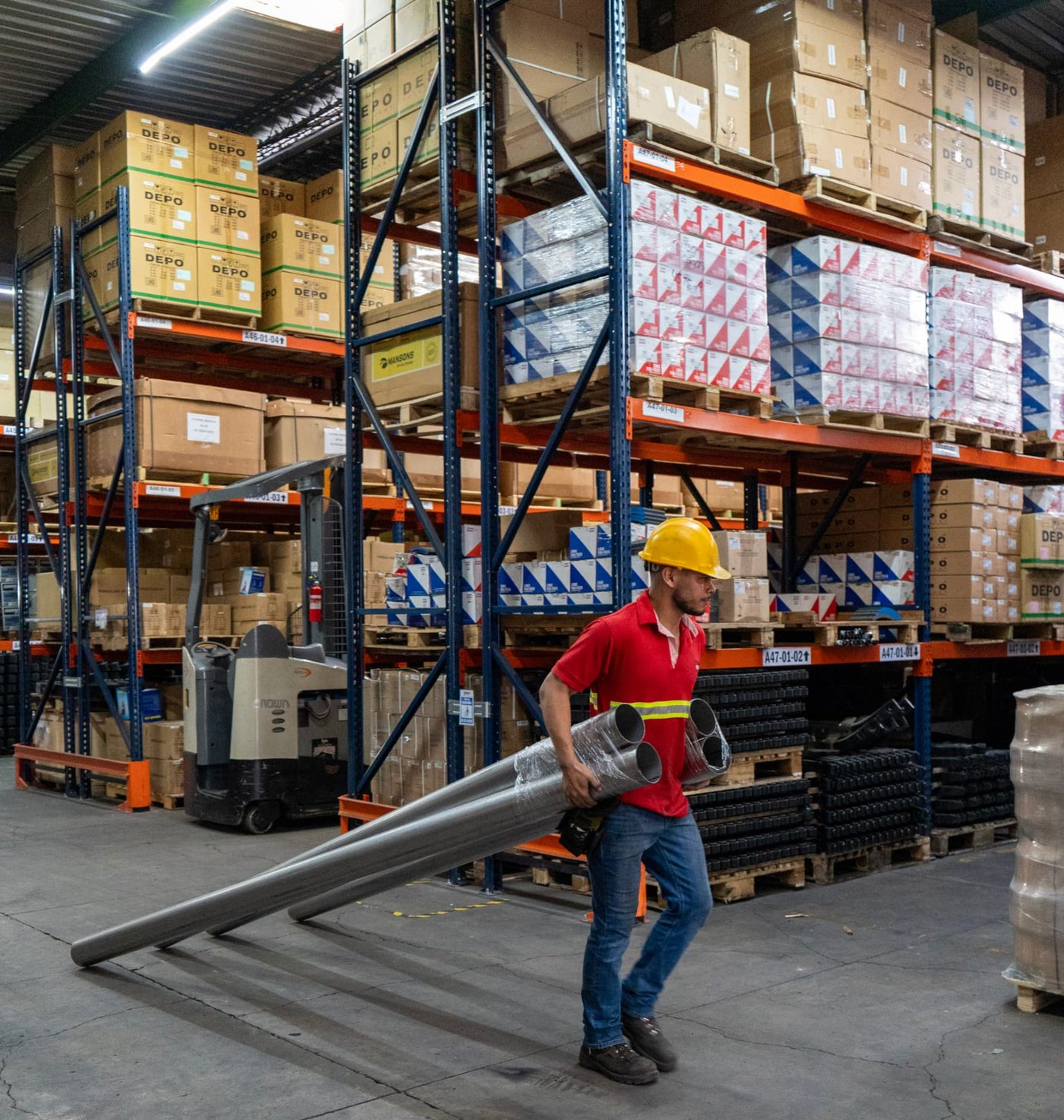 Colaborador trasladando tubería en bodega